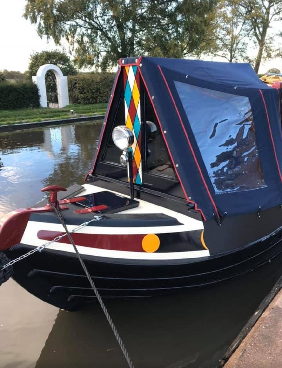 Colourful narrowboat bow with diamond pattern and professional paint finish on the water