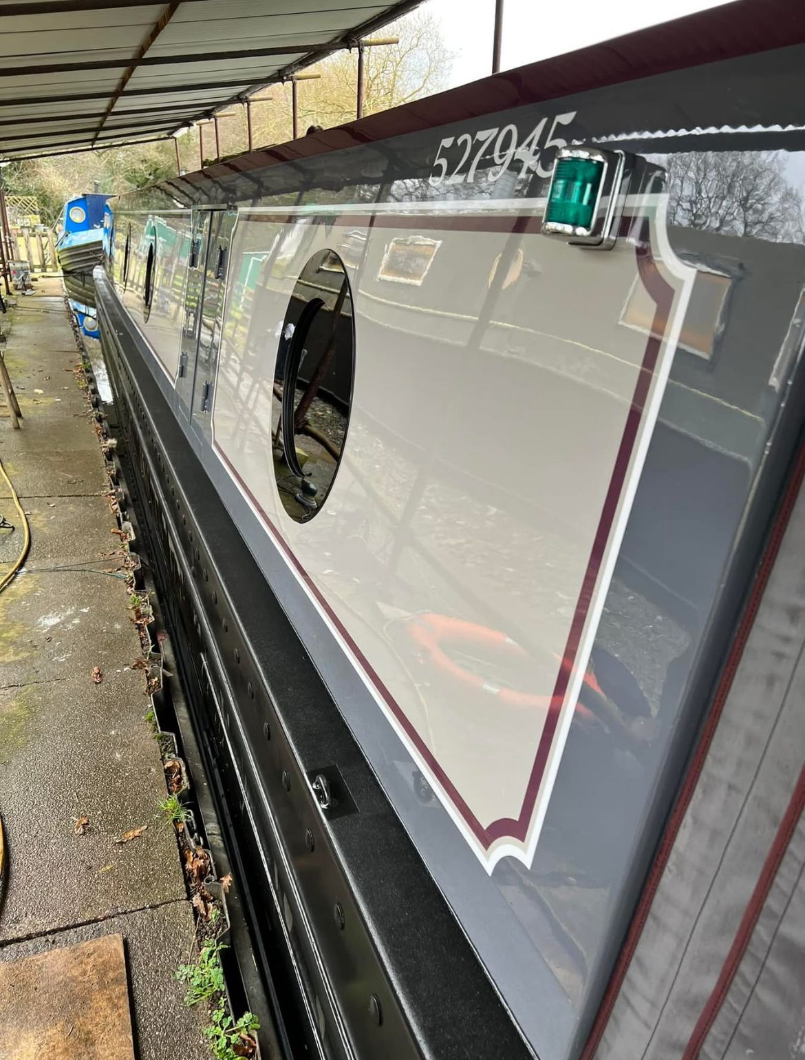 Grey and maroon narrowboat cabin side with coach lines and portholes