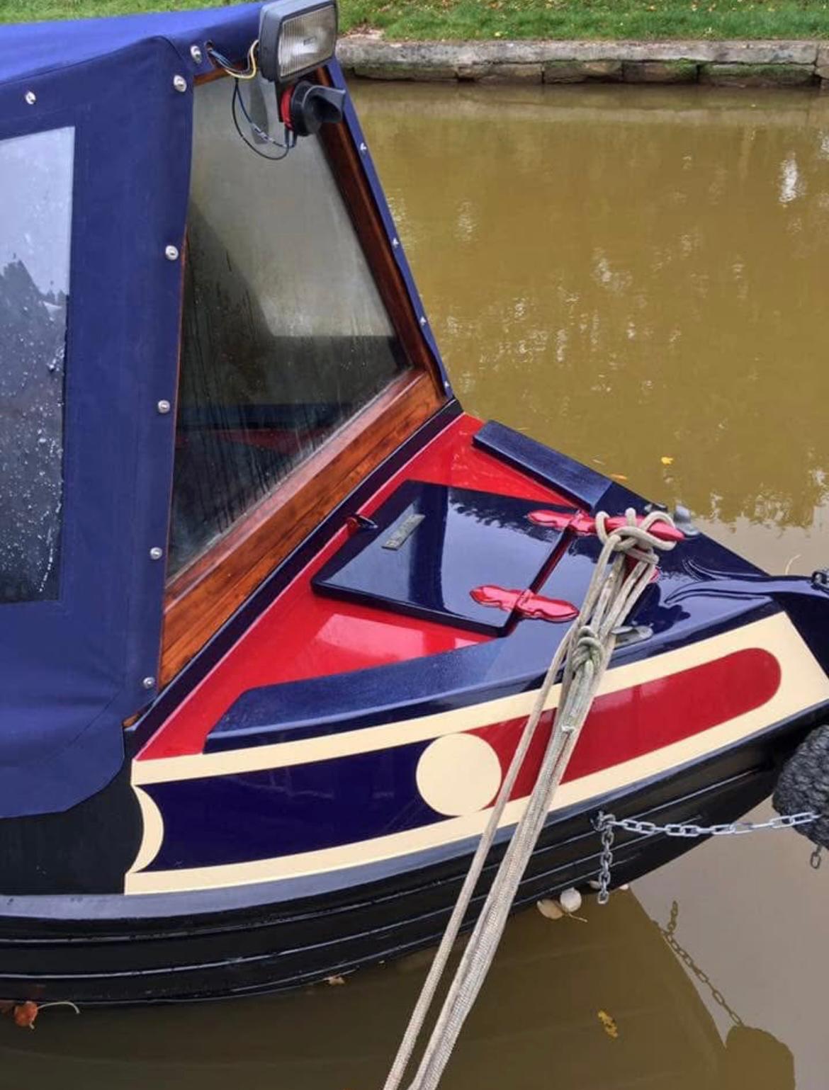 Red blue and cream narrowboat bow with gloss finish moored on the water
